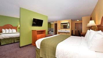 Habitación de hotel con dos camas, televisión, escritorio y espejo.