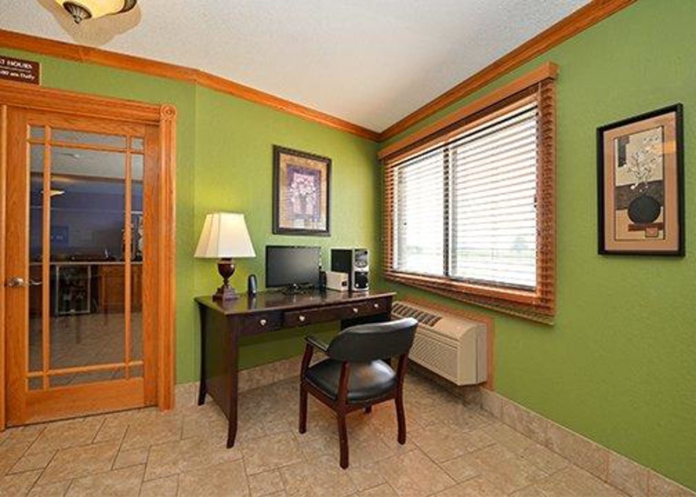 A room with a desk, chair, window with blinds, radiator, and a door.