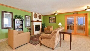 A living room with a fireplace, green walls, and a view through glass doors. - Quality Inn & Suites Grinnell near University (Grinnell)