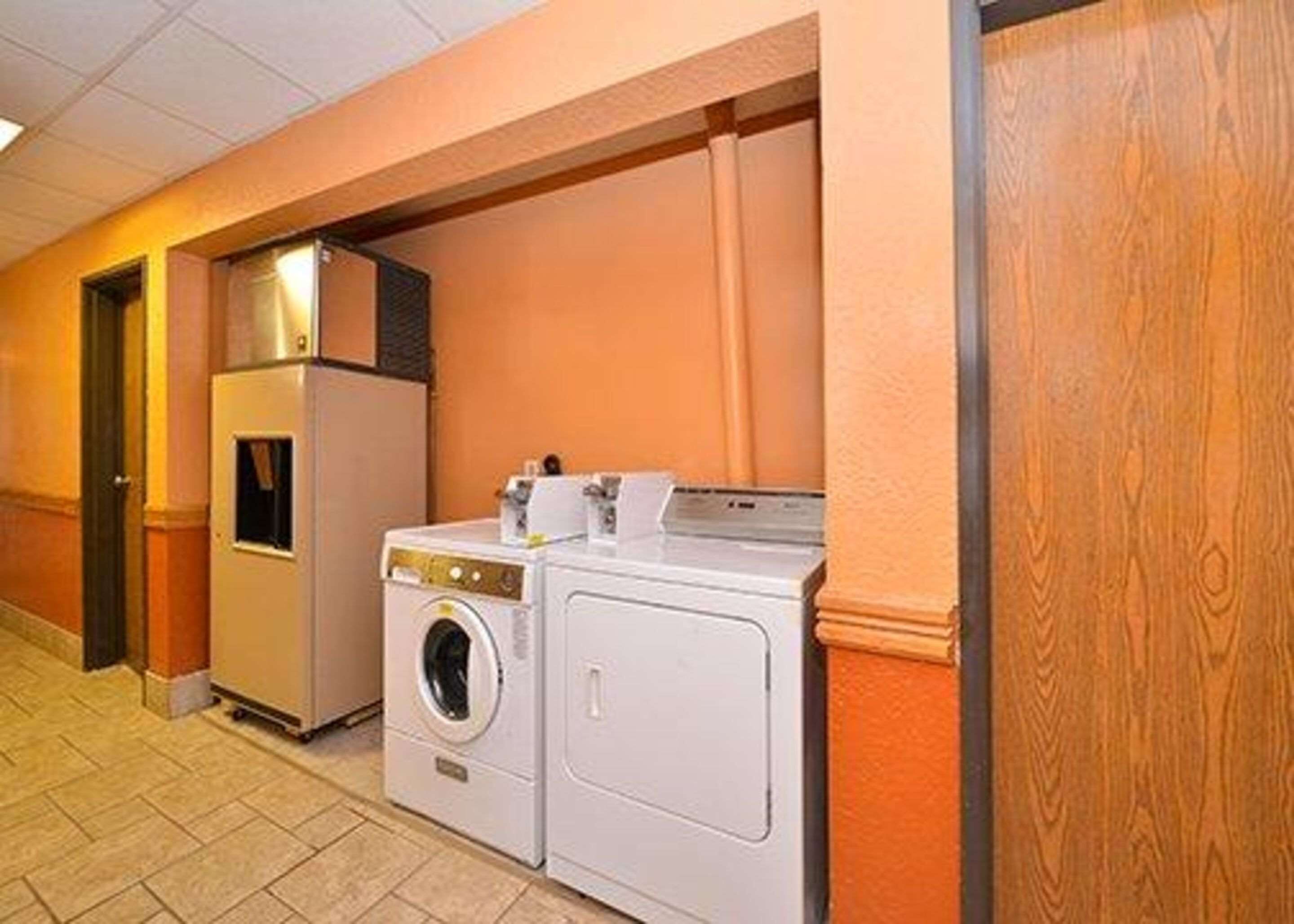 A laundry room with a washing machine and dryer, a small cabinet, and a door leading to another room.
