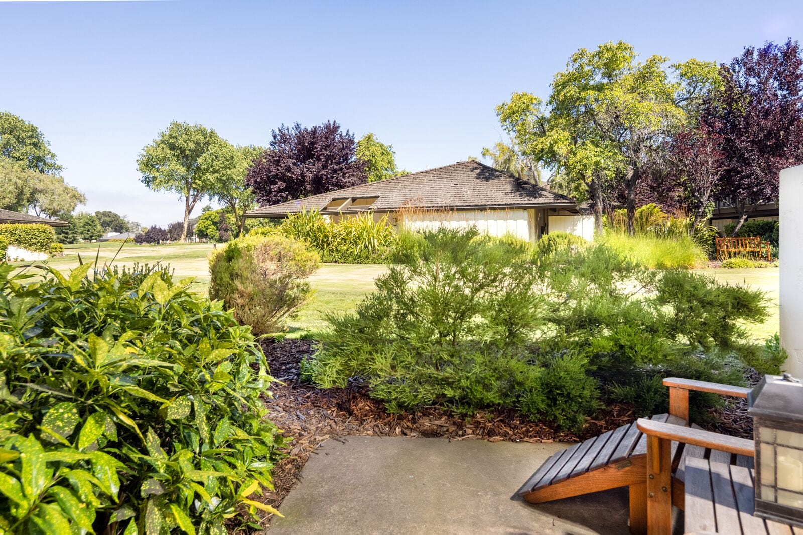 A residential property with a well-maintained lawn, a wooden deck, and a house with a sloped roof.