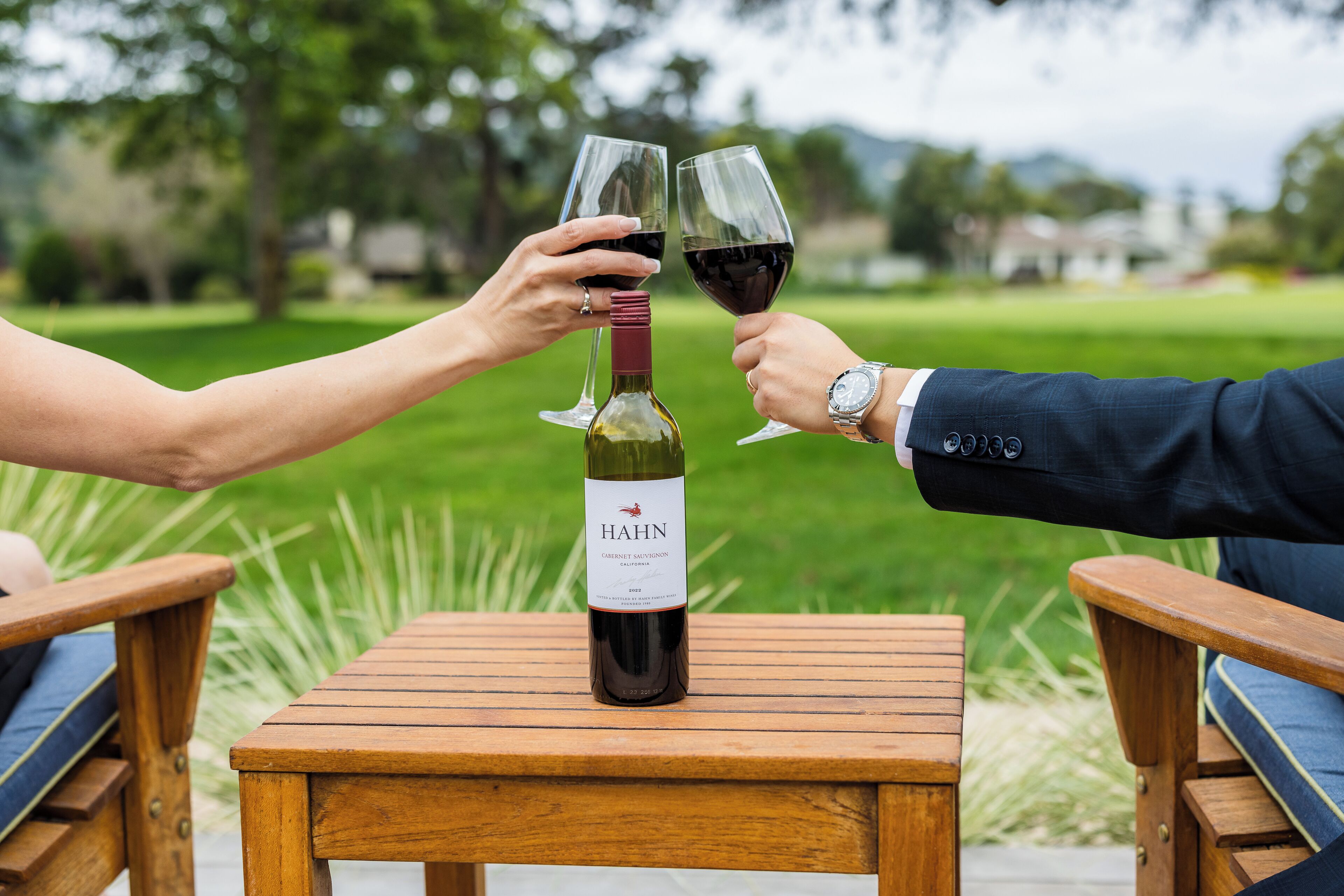 A wooden table with a bottle of wine and two glasses.