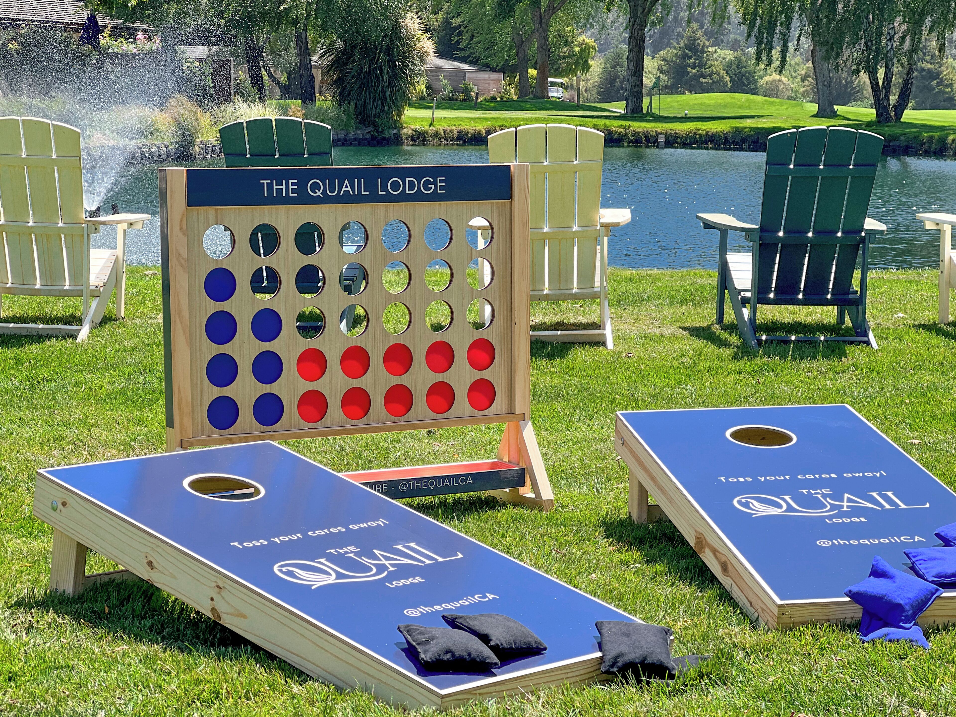 A lawn game setup with a board game and two shuffleboard tables, labeled "The Quail Lodge".