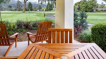 Una mesa y sillas de madera en un patio con vistas a un campo de golf.