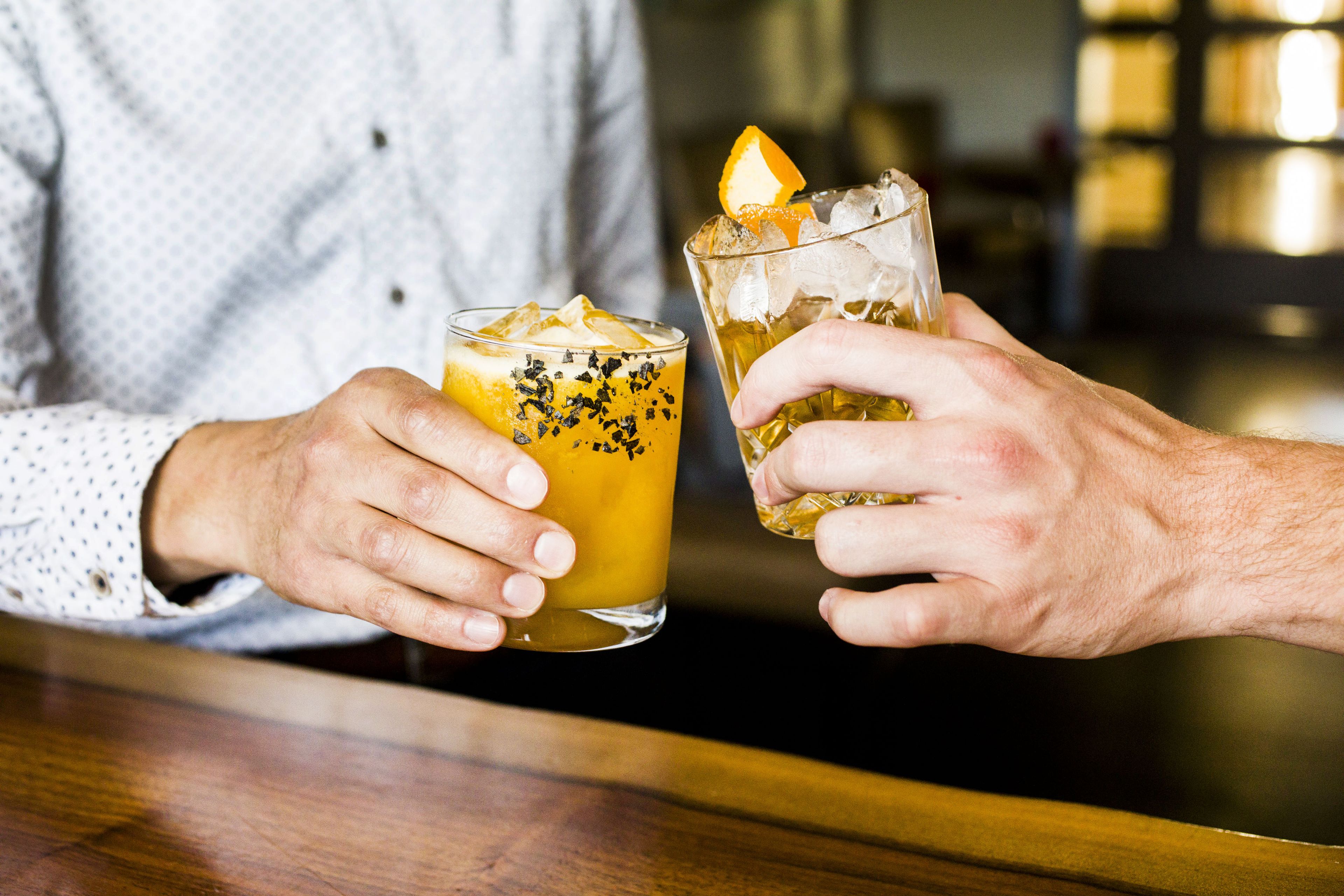 Dos personas sosteniendo vasos con bebidas en un bar.