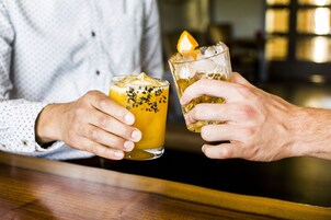 Dos personas sosteniendo vasos con bebidas en un bar.