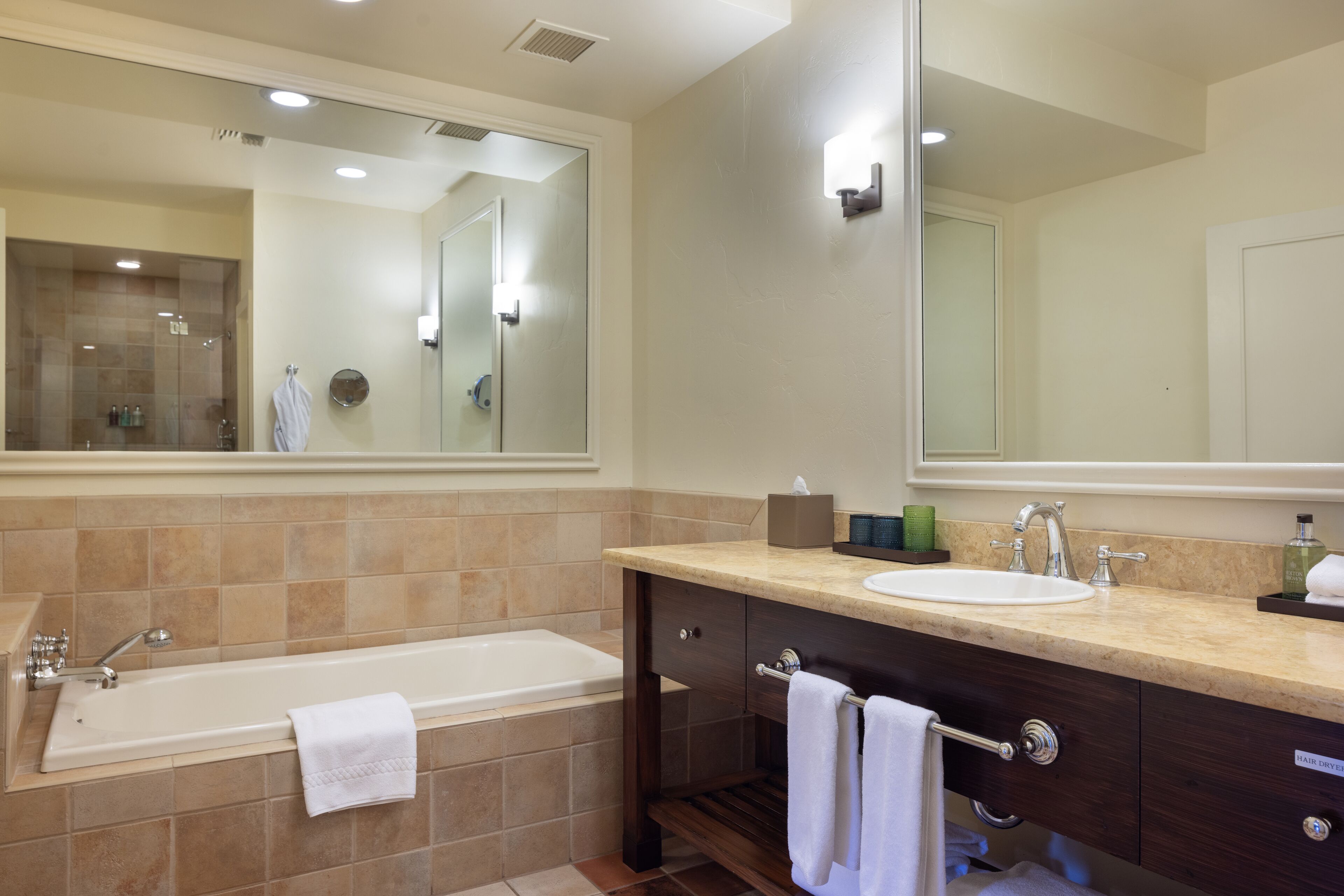 A modern bathroom with a large bathtub, a sink, and a vanity with a mirror.