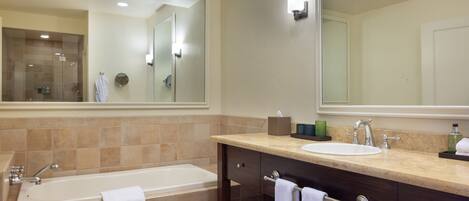 A modern bathroom with a large bathtub, a sink, and a vanity with a mirror.