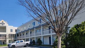 Un motel de varios pisos con fachada blanca y balcones. Una camioneta pickup blanca está estacionada en la entrada.