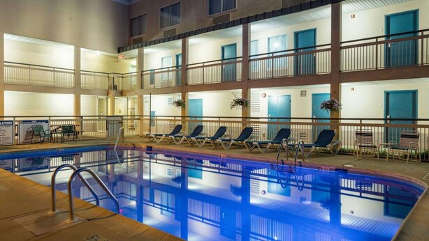 Un hotel de varios pisos con piscina, balcones y sillas de descanso.