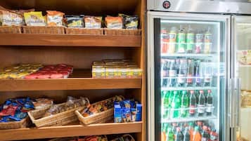 A snack and beverage display area with shelves stocked with various snacks and a refrigerator filled with bottled drinks.