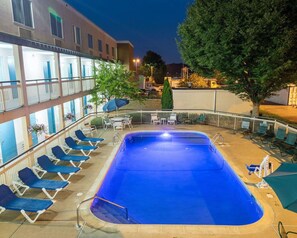 A rectangular swimming pool with a metal ladder, surrounded by lounge chairs and umbrellas.