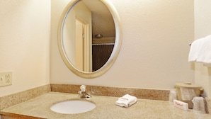 A bathroom with a round mirror, a sink, and a towel rack. - Red Roof Inn Akron (Akron)