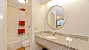 A bathroom with a shower, toilet, sink, and a mirror. - Red Roof Inn Akron (Akron)