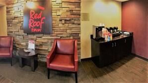 A Red Roof Inn reception area with two leather chairs, a coffee station, and a stone wall. - Red Roof Inn Akron (Akron)