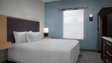 Une chambre d’hôtel bien aménagée, avec un grand lit, une table de chevet avec une lampe, une fenêtre donnant sur un beau paysage et un téléviseur posé sur un meuble.