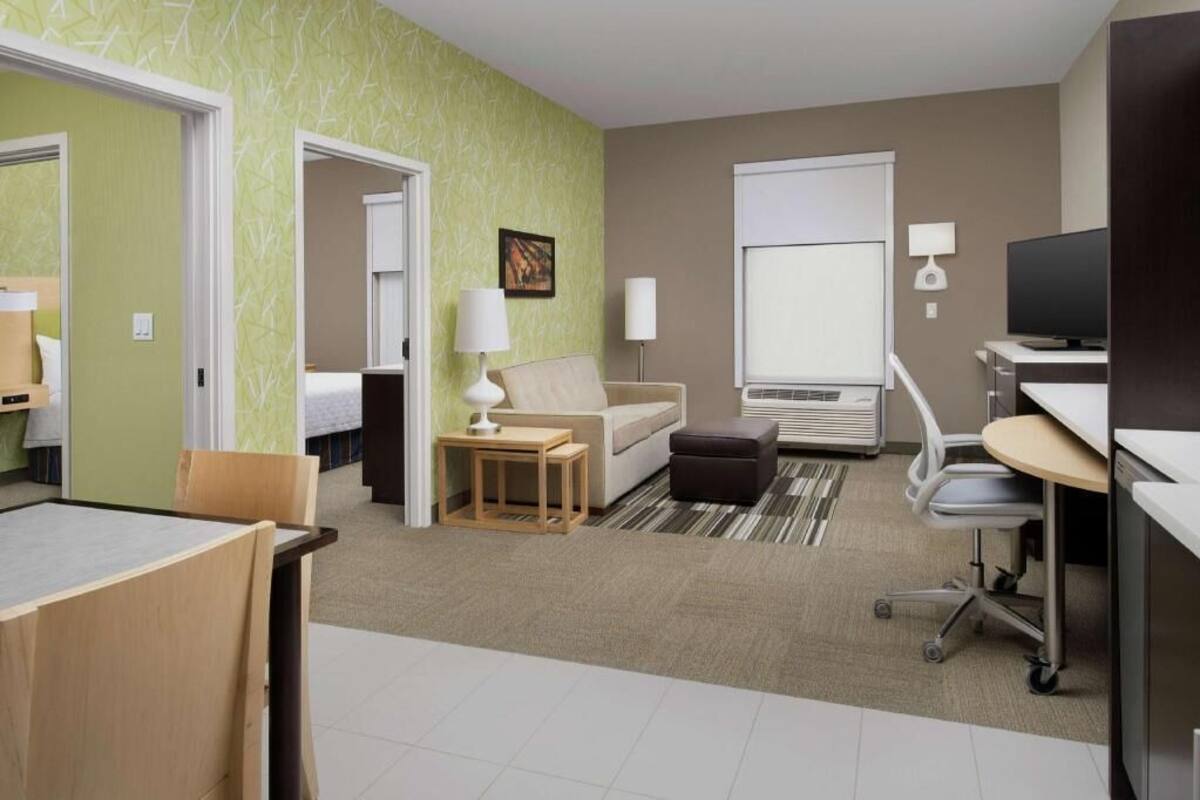 A hotel room with a bed, a desk, a chair, a TV, and a window.
