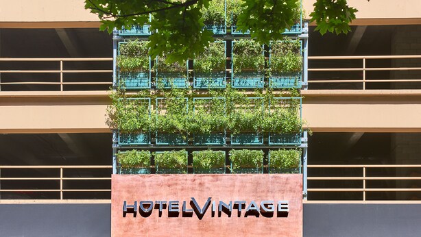 A building with a sign reading "HOTELVINTAGE" and a balcony with greenery. - Kimpton Hotel Vintage Seattle by IHG (Seattle)