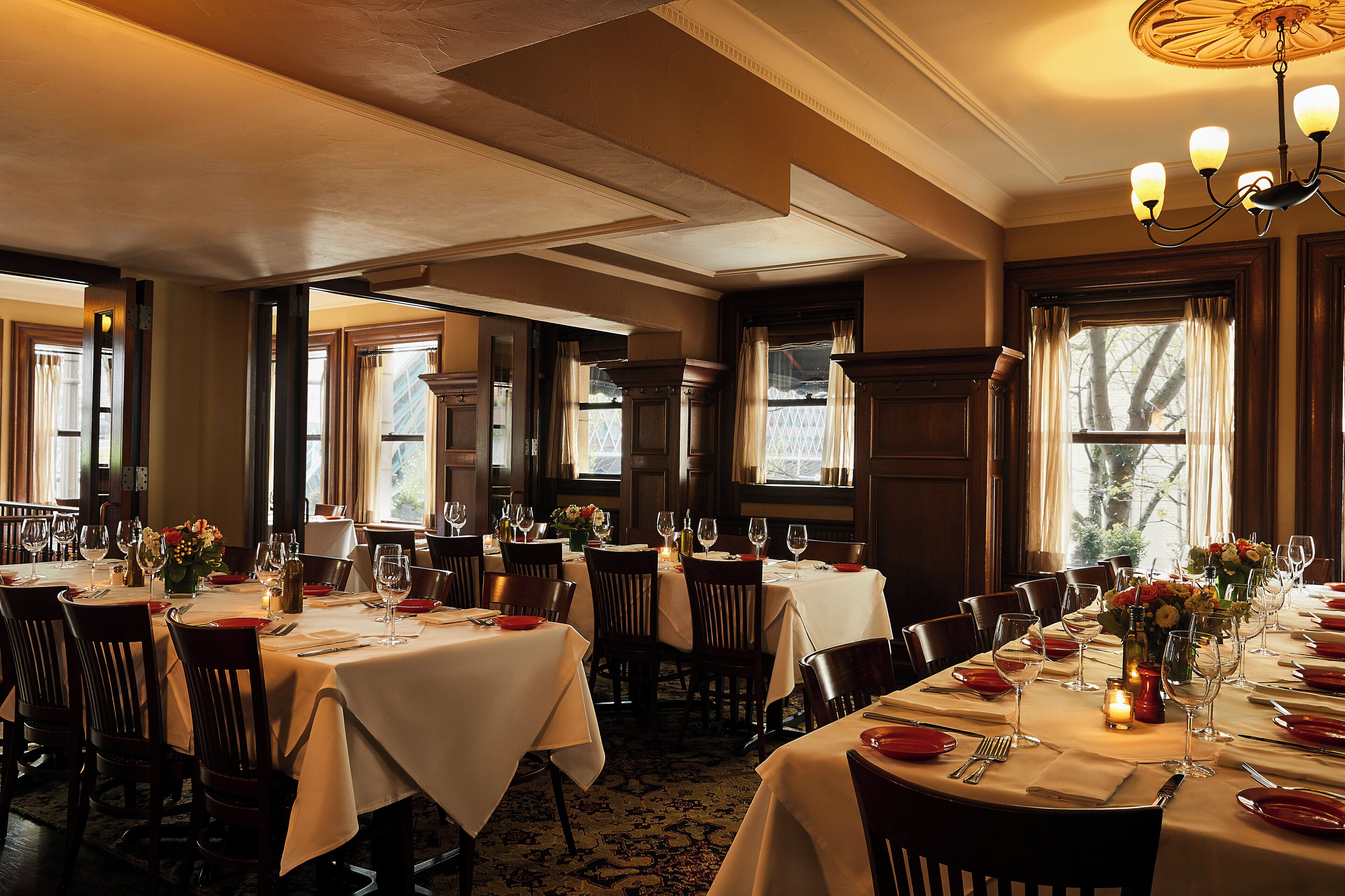 A dining area with multiple tables set for a meal, featuring chairs, tablecloths, and table settings.