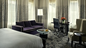 A hotel room with a bed, a sofa, a desk with a chair, a lamp, and a vase with flowers. - Kimpton Hotel Vintage Seattle by IHG (Seattle)