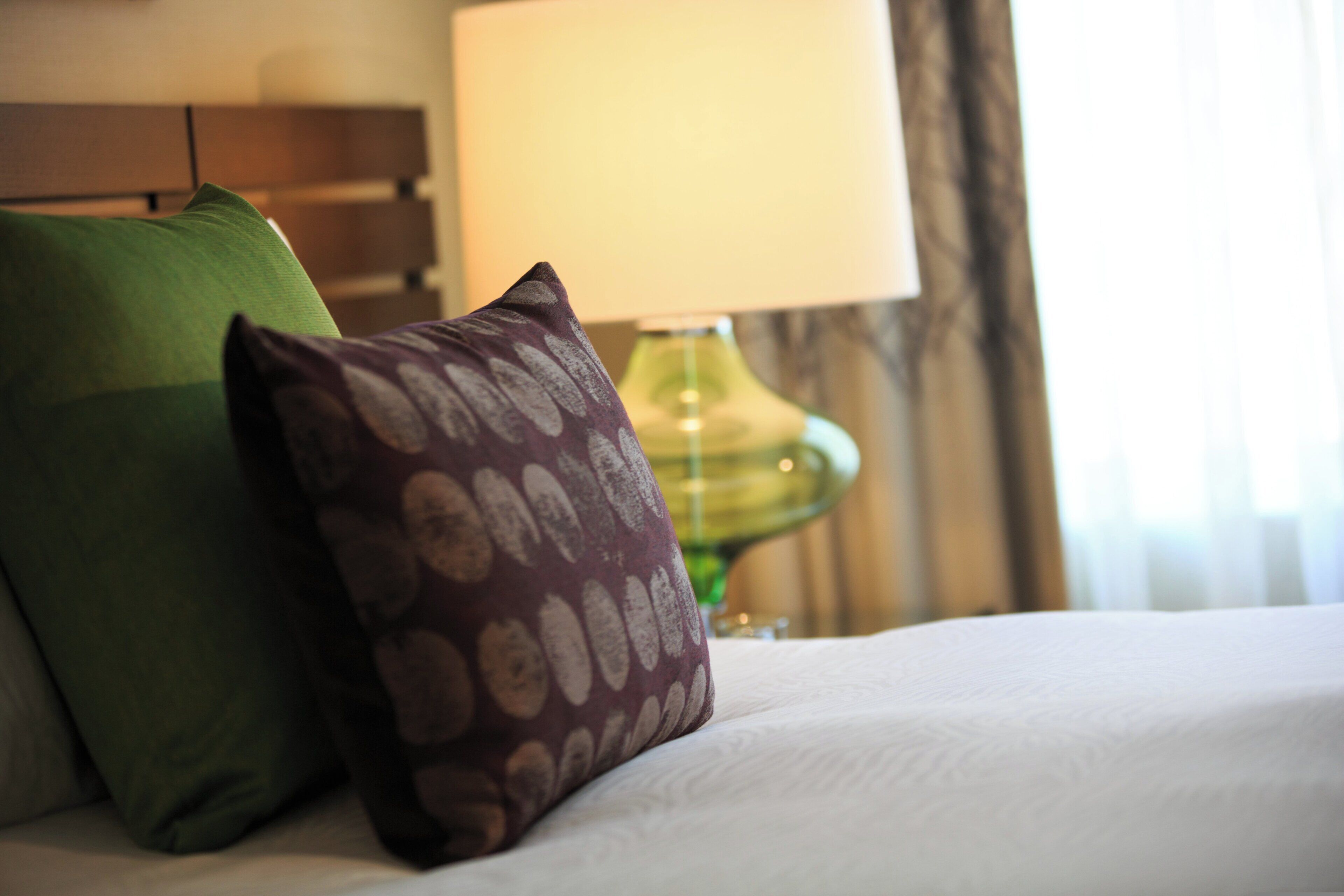 A bed with pillows and a lamp in a hotel room.