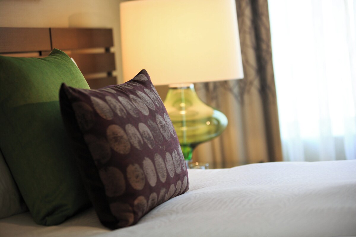 A bed with pillows and a lamp in a hotel room.