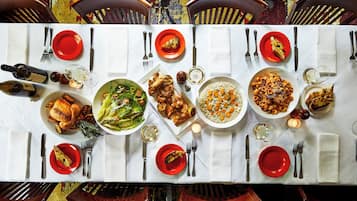 Une table à manger dressée pour un repas, avec différents plats et des verres à vin.