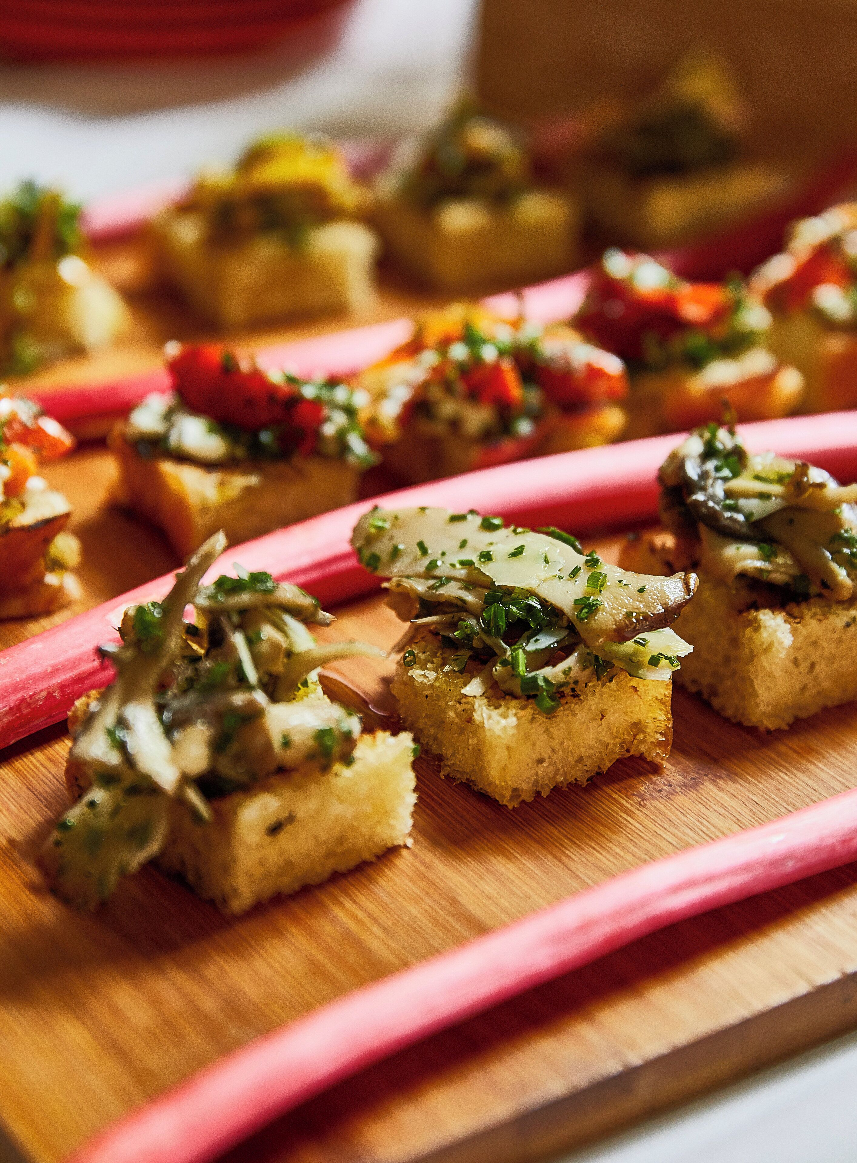 Una tabla de madera con varias bruschettas cubiertas con diferentes ingredientes.