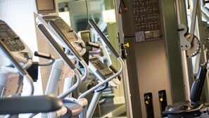 A row of stationary exercise bikes in a gym with mirrors on the walls. - Kimpton Hotel Vintage Seattle by IHG (Seattle)