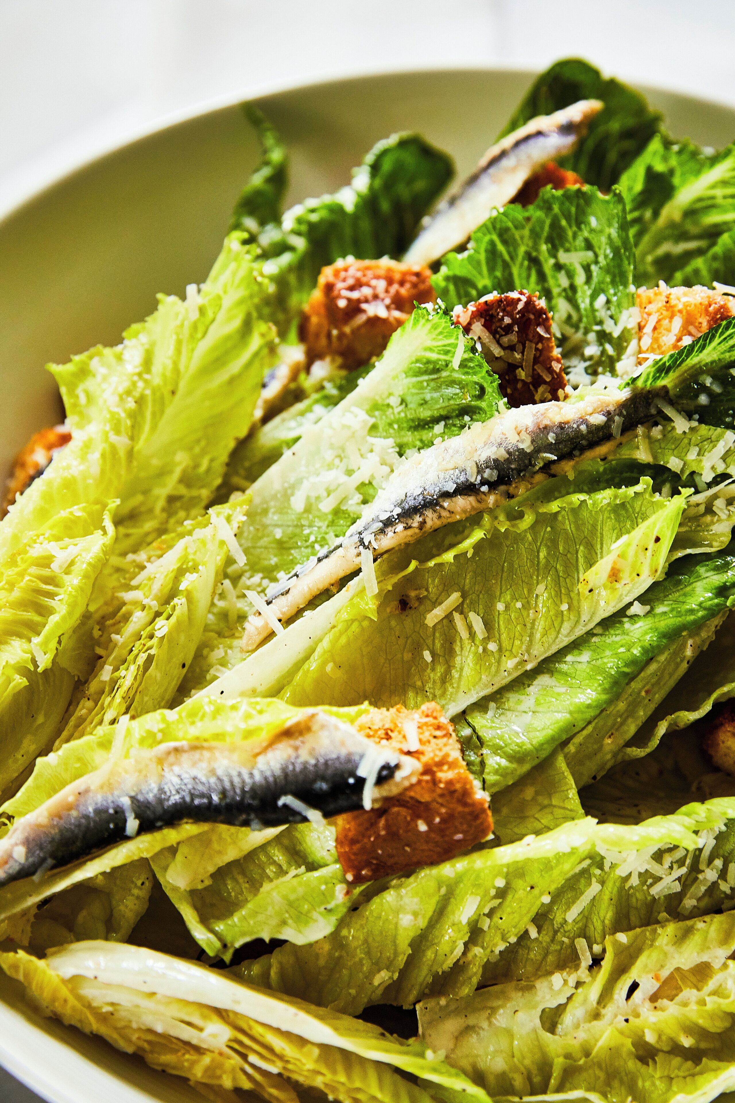 Un'insalata con lattuga, crostini e pesce.