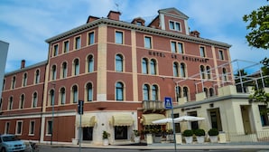 Historiallinen rakennus, jonka yläpuolella on kyltti, jossa lukee ”HOTEL LE BOULEVARD”. Siinä on useita ikkunoita, parveke ja ulkotila, jossa on istuimia ja aurinkovarjoja.
