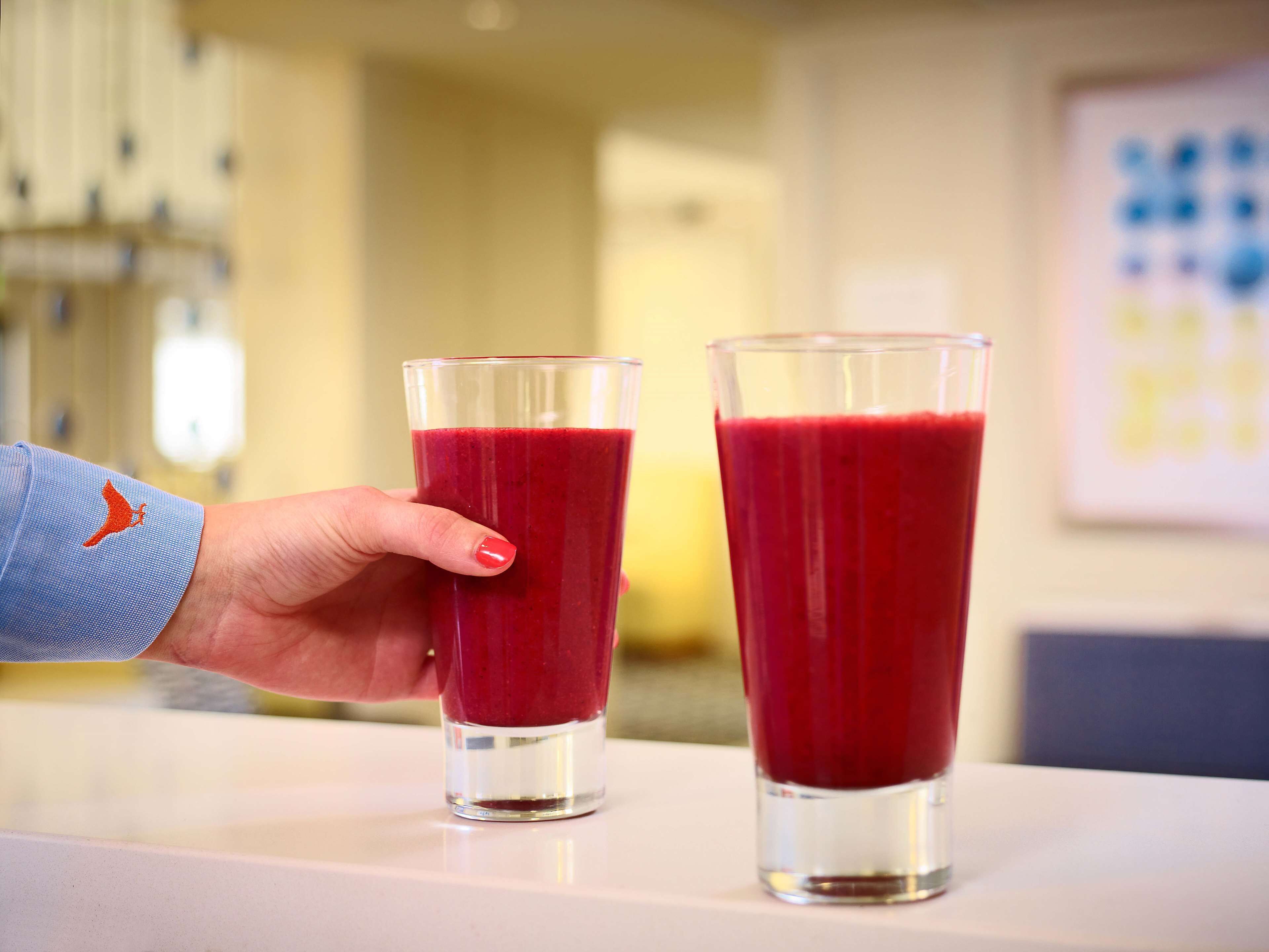 Two glasses of red beverage on a table.
