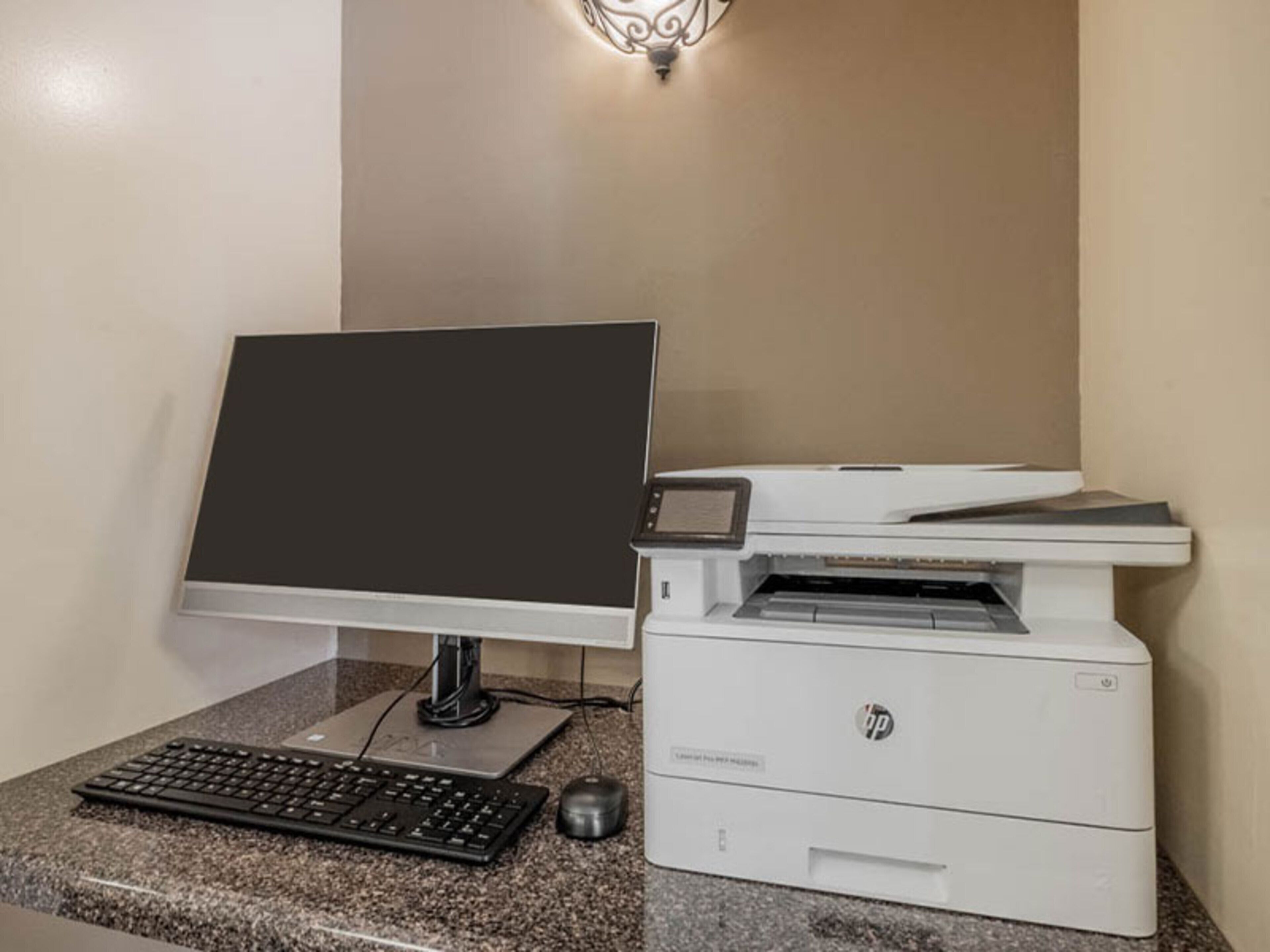 A desktop computer with a monitor, keyboard, and HP printer on a granite countertop.