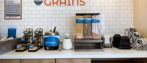 Una barra de desayuno con recipientes etiquetados de cereales, yogur y avena.