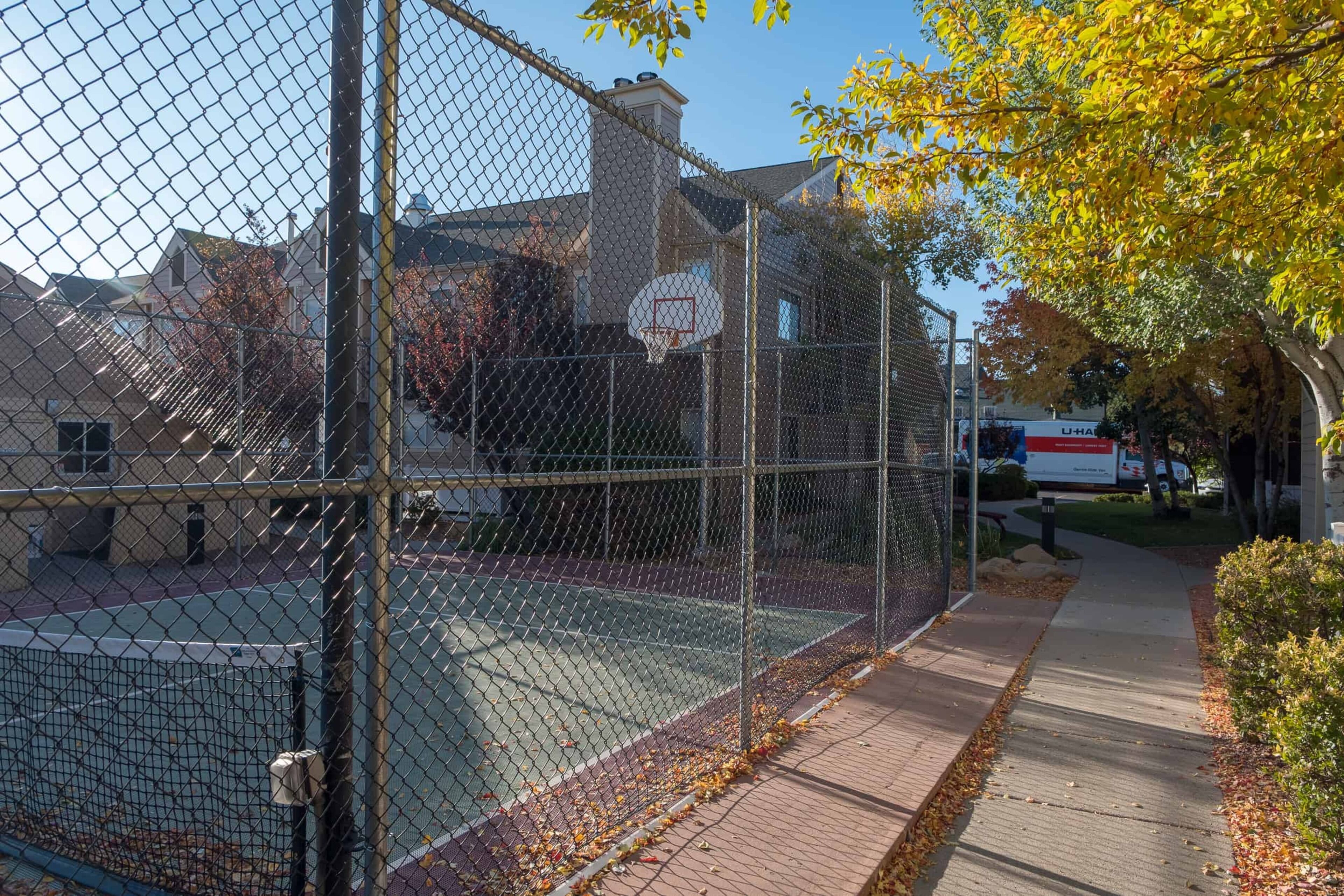 A fenced basketball court with a visible basketball hoop.