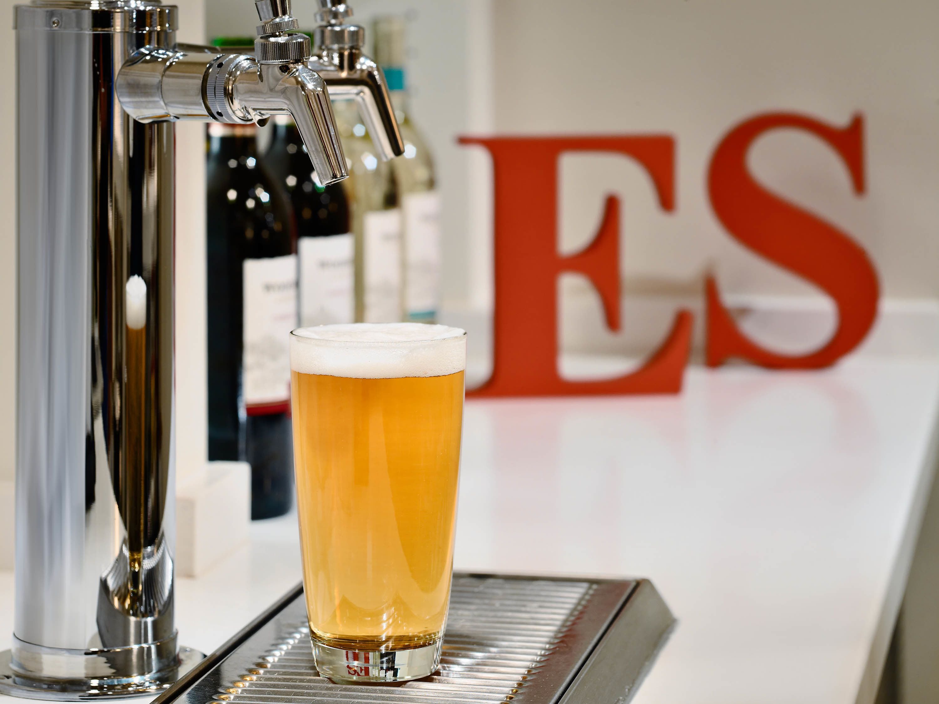 Un robinet à bière avec un verre de bière devant.