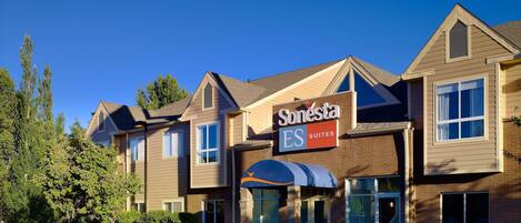 A Sonesta hotel with a brick facade, multiple windows, and a clear blue sky.