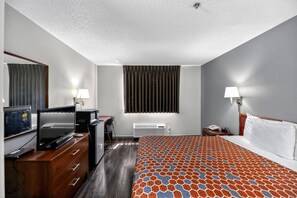A hotel room with a bed, a desk with a computer, a TV, and a window with blinds. - Econo Lodge Princeton (Princeton)