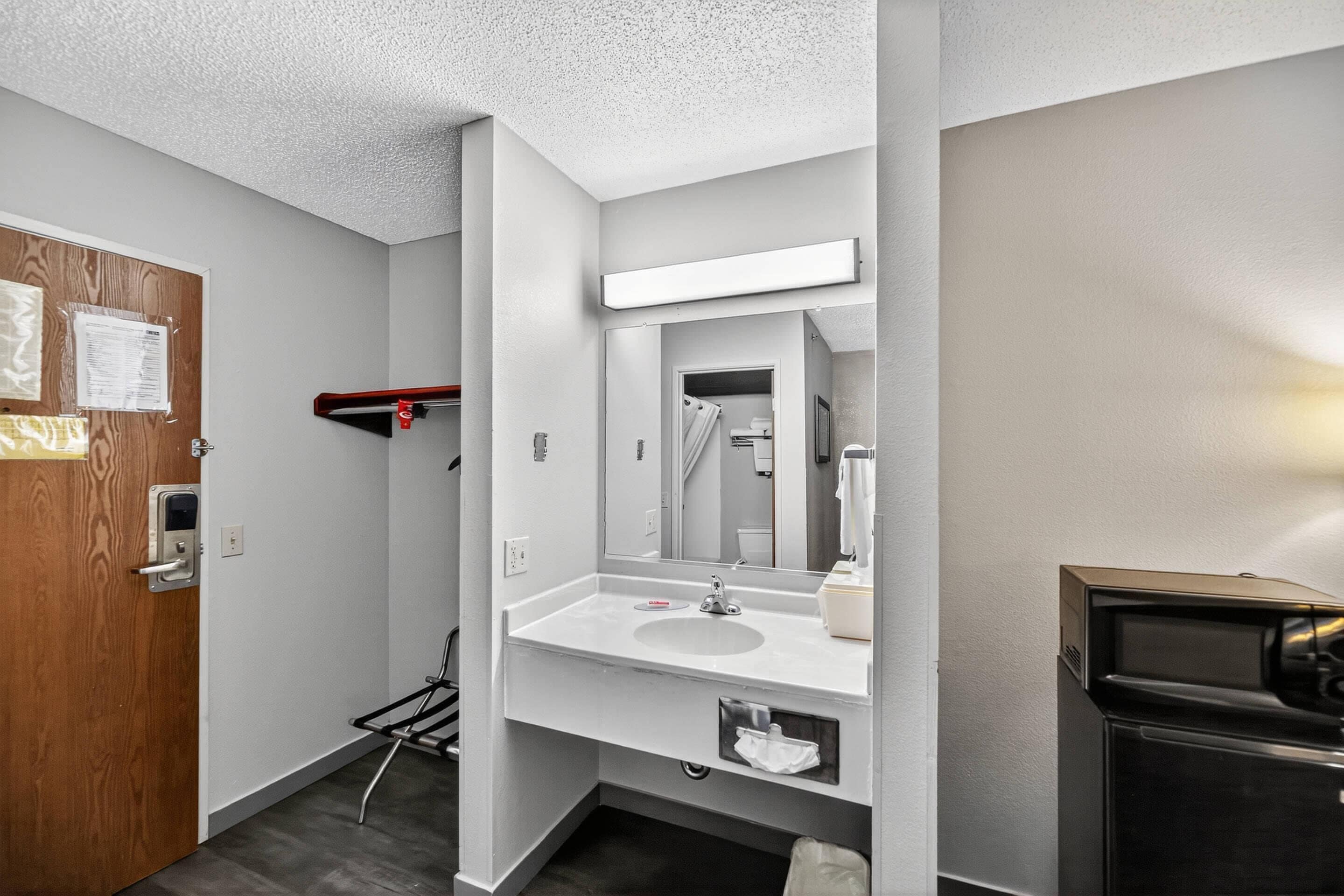 A modern bathroom with a white sink, mirror, and towel rack.