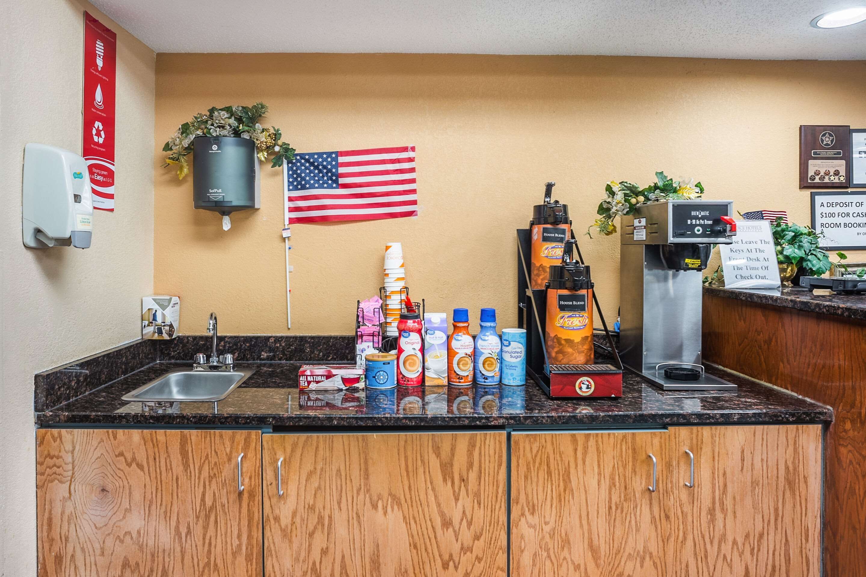 A hotel reception area with a marble counter, a coffee machine, a sink, and a flag.