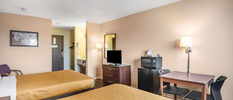 A hotel room with two beds, a desk with a chair, a television, a refrigerator, and a lamp.