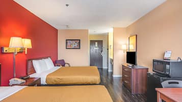A hotel room with two beds, a desk with a microwave, a TV, and a dresser.