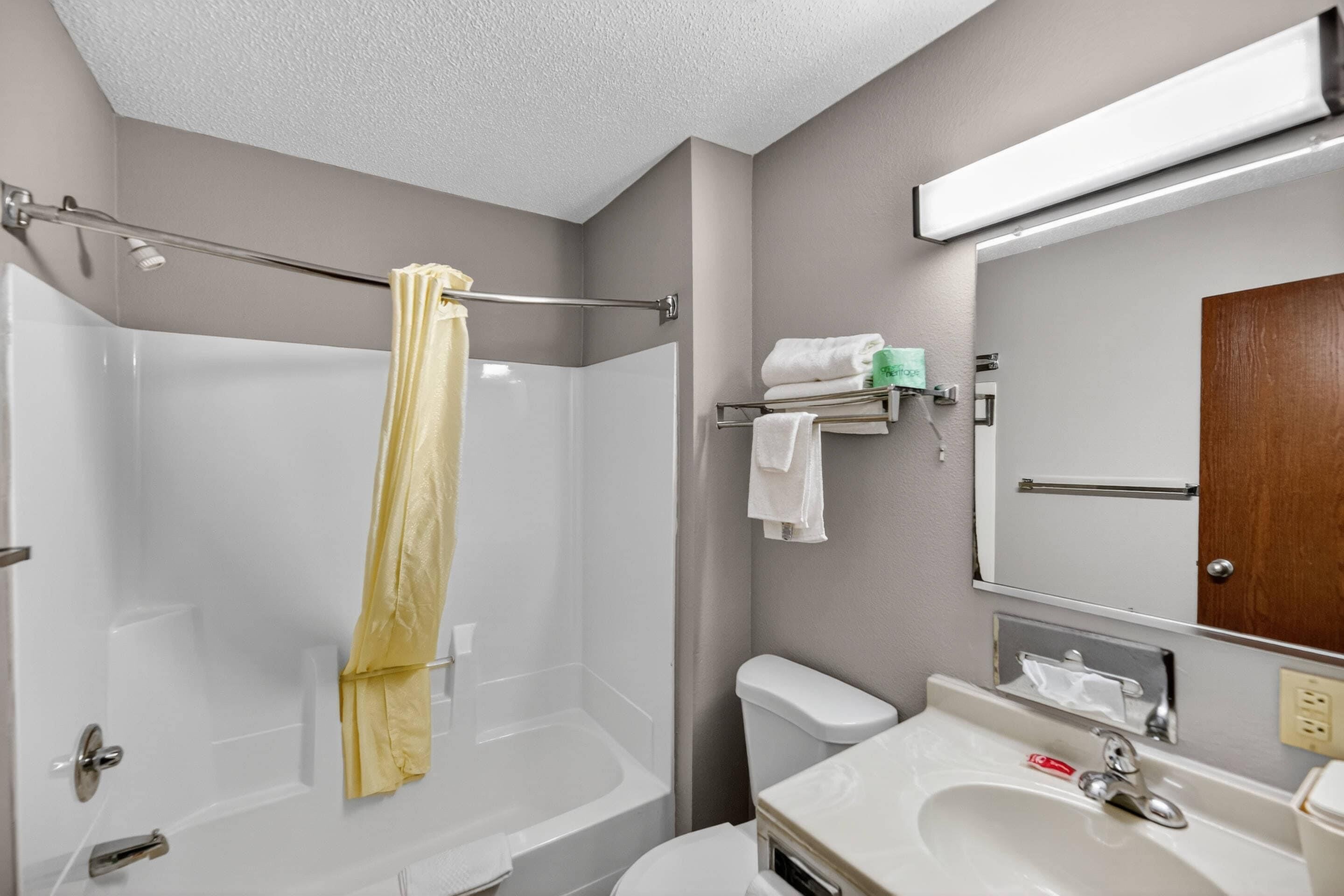 A bathroom with a bathtub, toilet, sink, and a towel rack with towels.