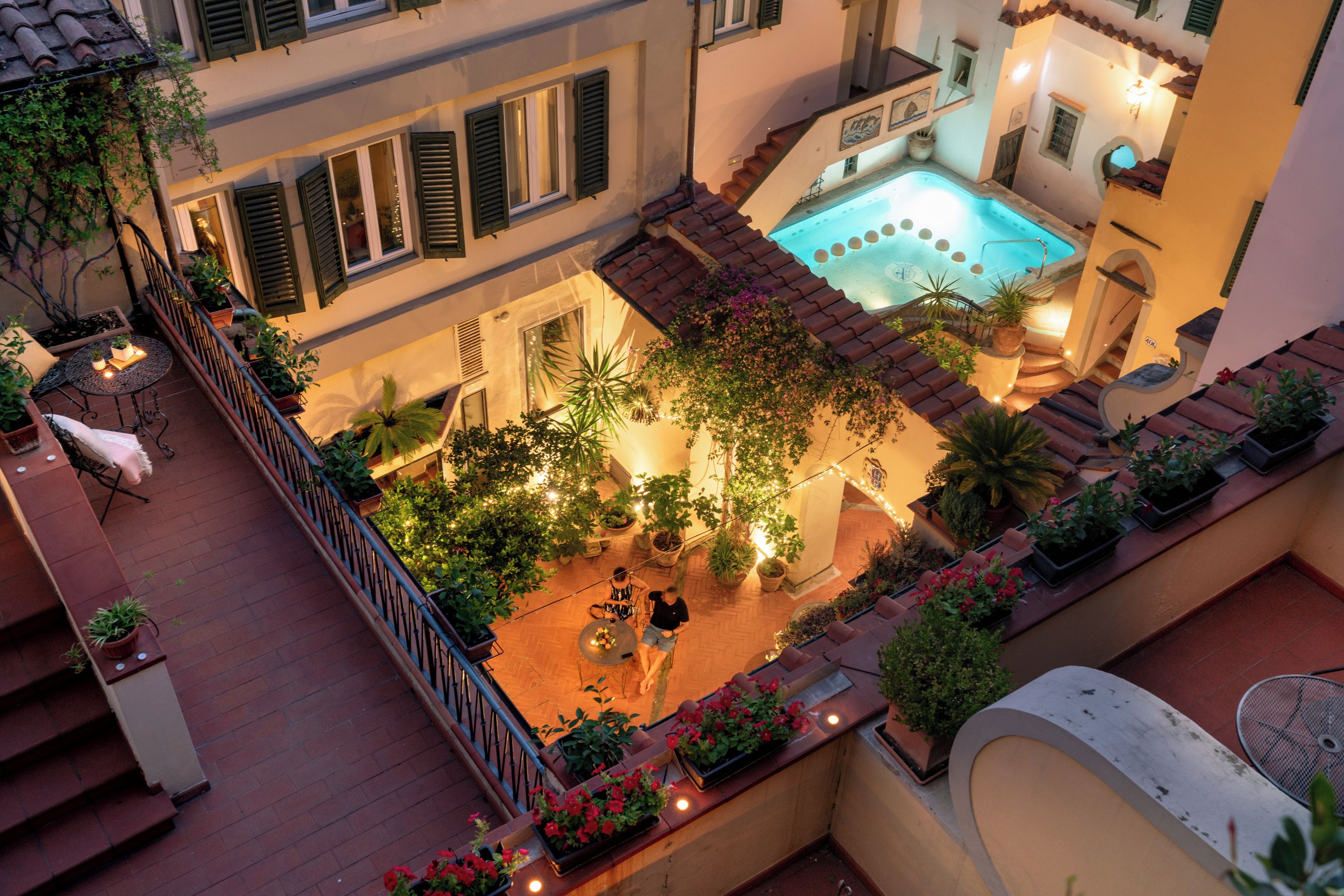 Eine Dachterrasse mit Pool, Topfpflanzen und Sitzgelegenheiten im Freien.