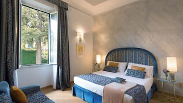 Un dormitorio con una cama grande, un sofá, una ventana con cortinas y una lámpara en una mesita de noche.