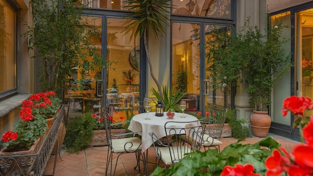 An outdoor patio with a round table, chairs, and potted plants.