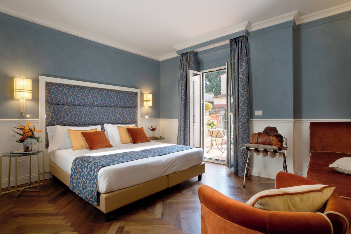 Une chambre à coucher avec un lit, une chaise, une table et une vue sur l’extérieur.