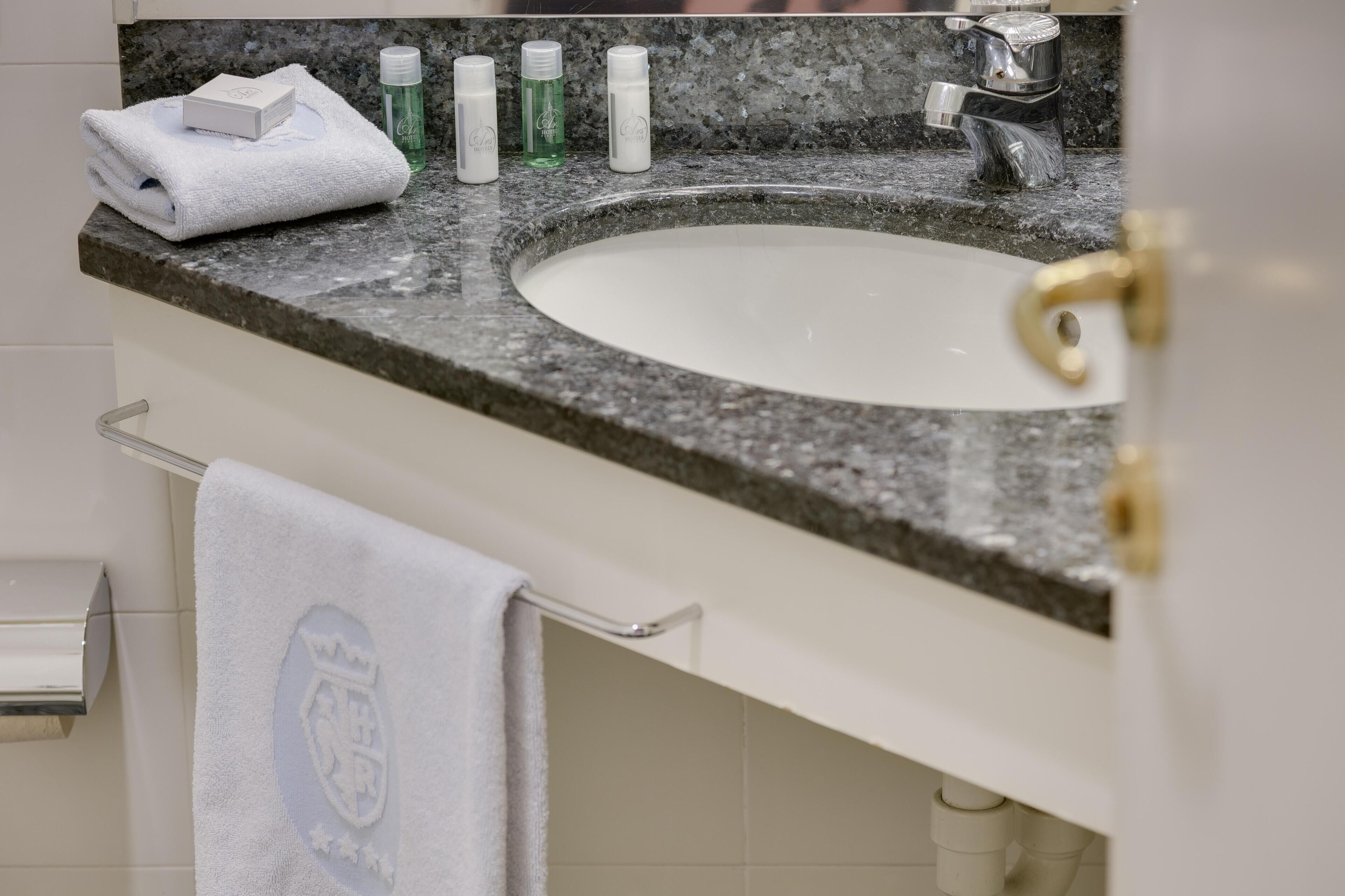 Une salle de bain avec un comptoir en granit, un lavabo blanc et des articles de toilette.