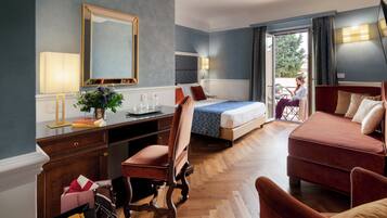Une chambre d’hôtel avec un lit, un bureau et une chaise, un canapé et une vue sur l’extérieur par une porte ouverte.