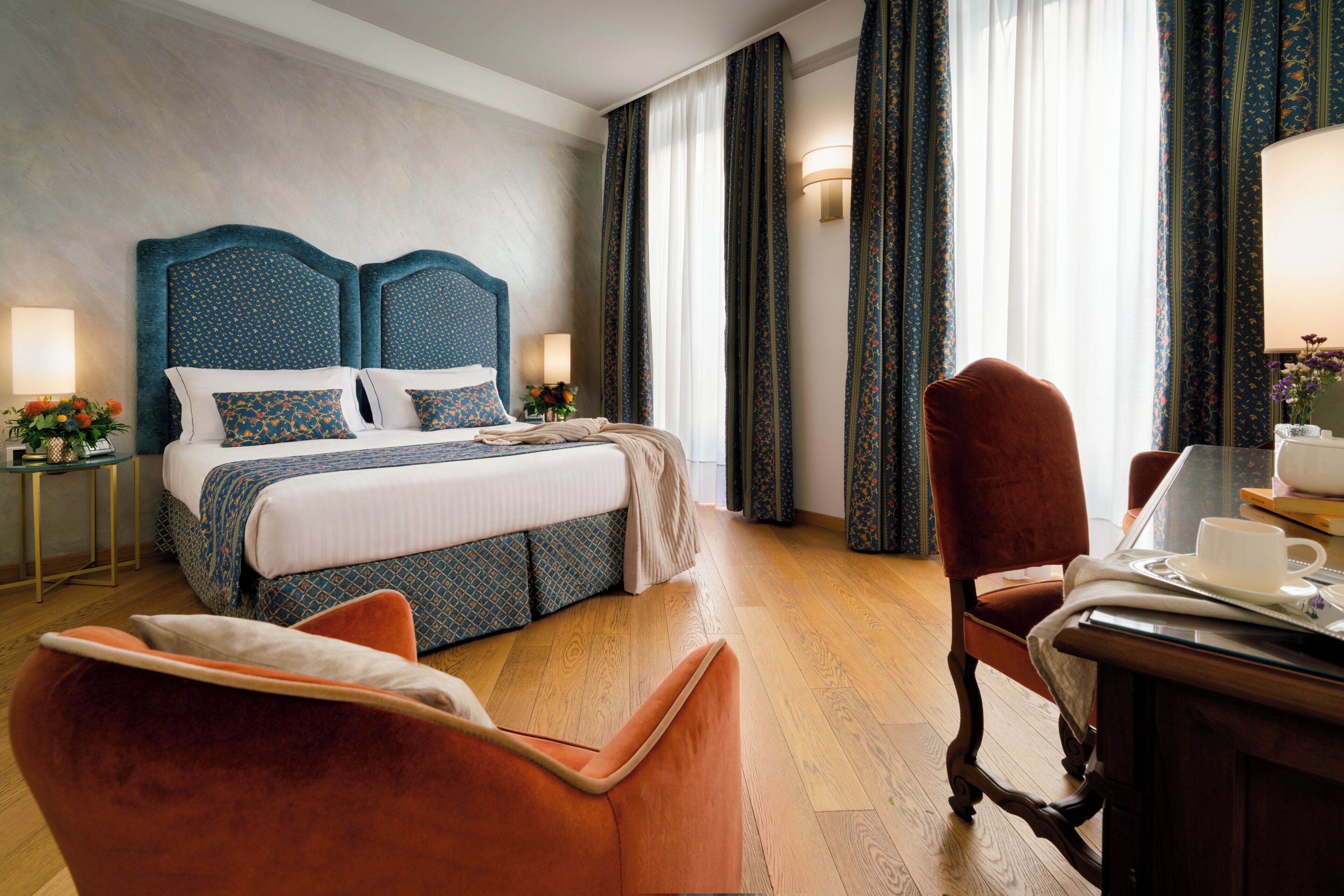 Une chambre d’hôtel avec un grand lit, un bureau avec une chaise et une fenêtre avec des rideaux.